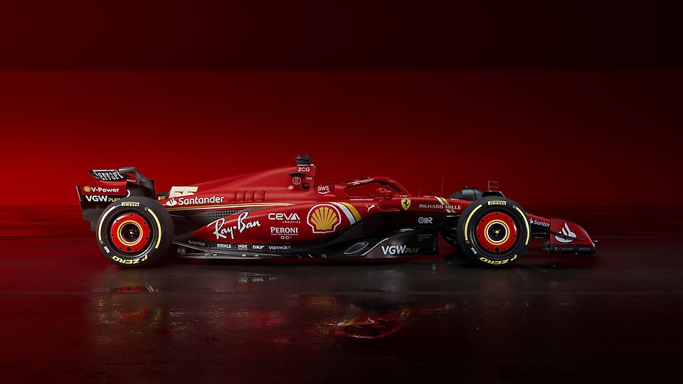 On a glossy floor a Ferrari race car is parked against a red backdrop.