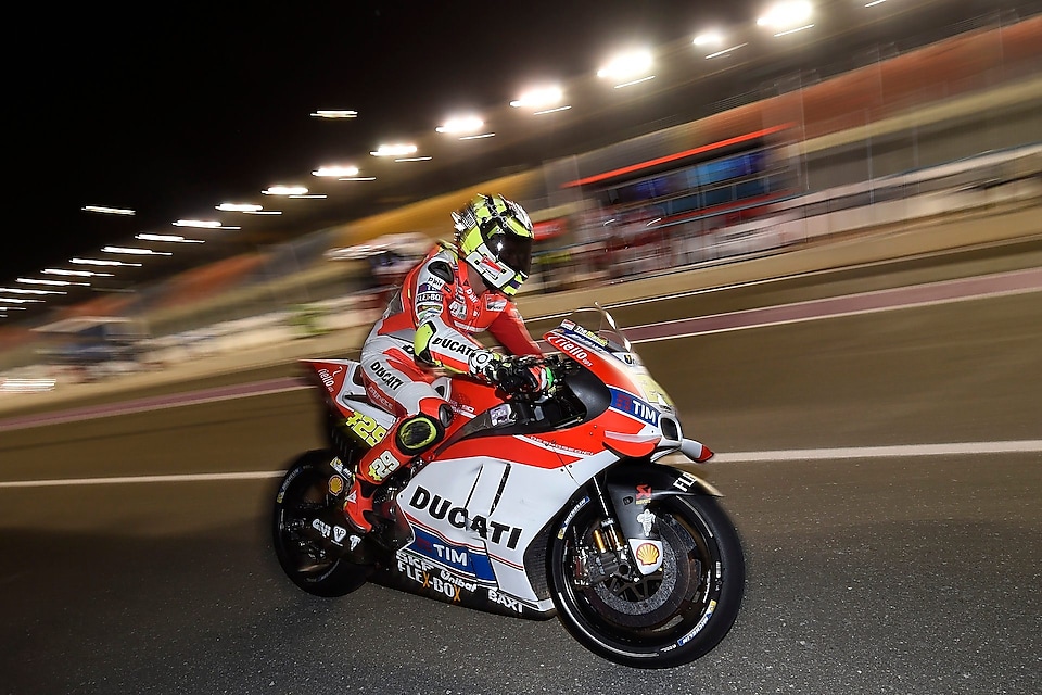 Ducati rider riding motorcycle at high speed on a track at night