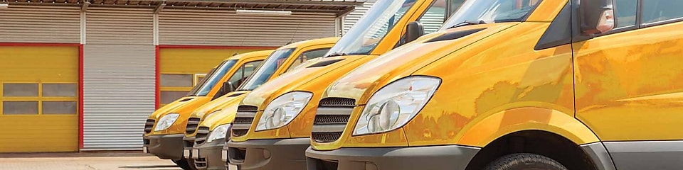 Une flotte de camionnettes jaunes devant un garage