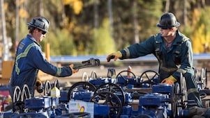 A man passes a tool to another worker at a Groundbirch well site.