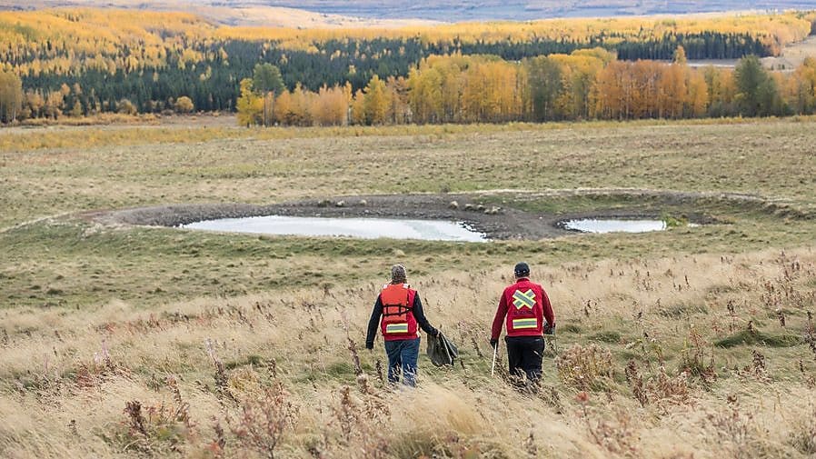 Two people walk towards a pond