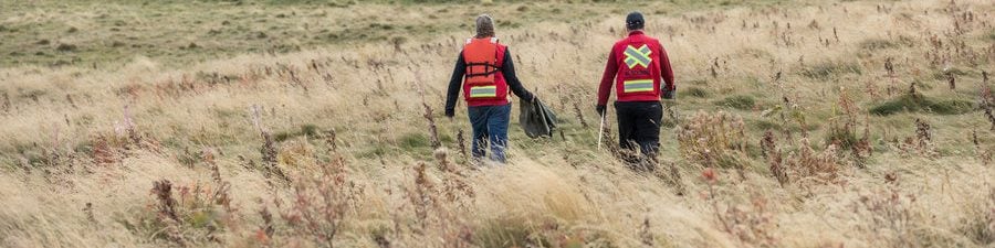 Two people walk towards a pond