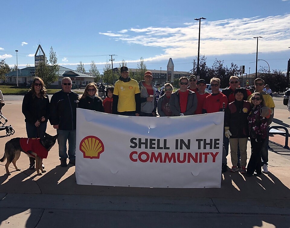 A group of Shell Groundbirch employee volunteers stand behind a banner at a community event.