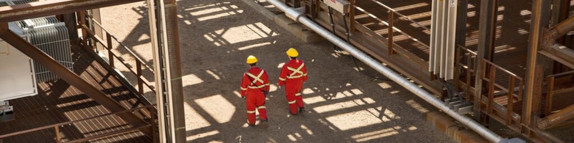 Two shell engineers in red dress walking in the factory