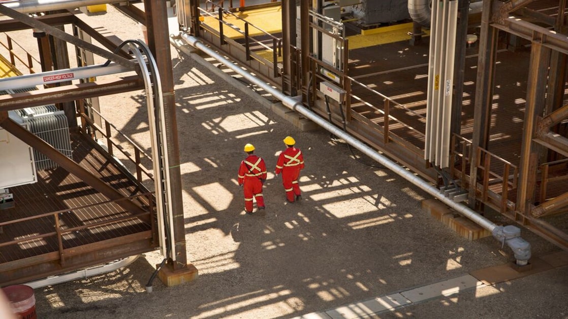 Two shell engineers in red dress walking in the factory