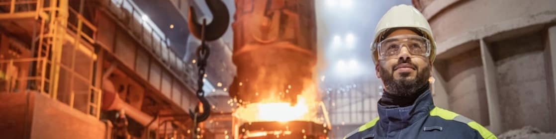 Worker in full PPE facing forward with furnace in the background