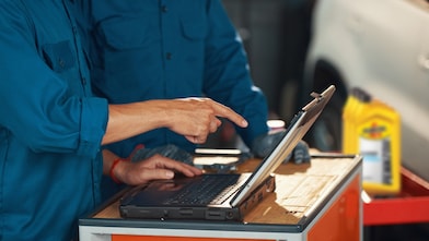 Two technicians using Shell resources and recommendations to select the right oil for each vehicle.