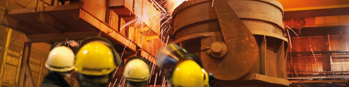 workers watching heavy machinery in a metal processing plant