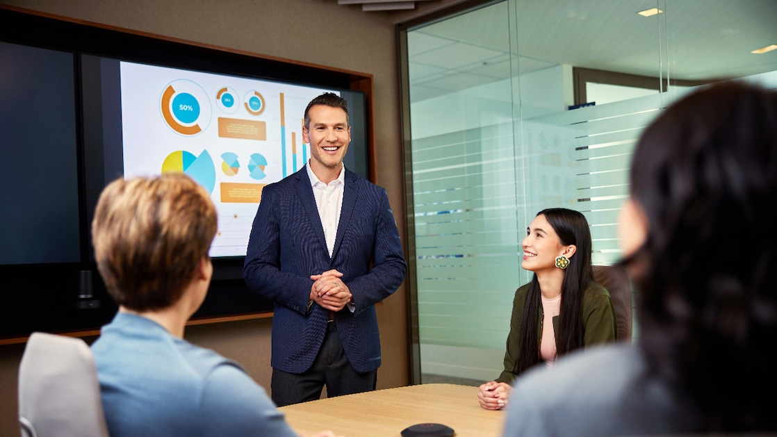 Professional presenting business performance metrics to colleagues during a team meeting in a modern office