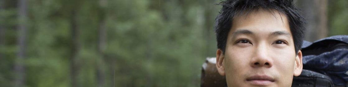 Portrait of Asian male backpacker in the woods