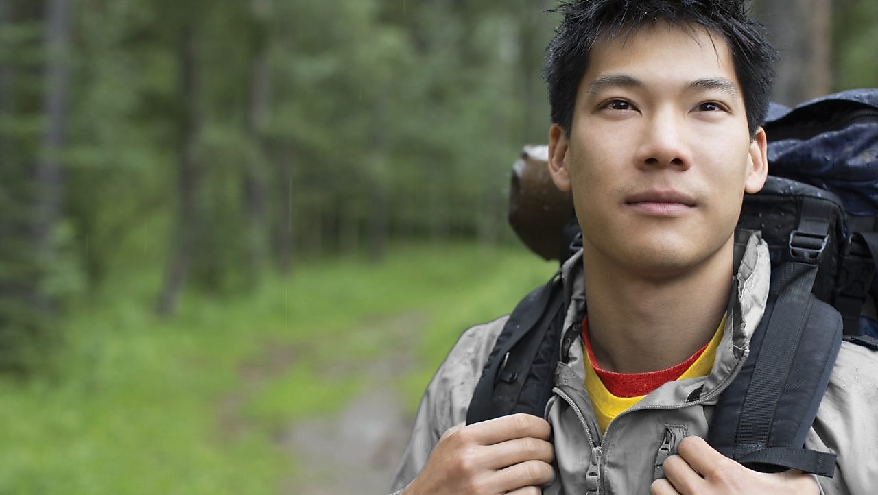 Portrait of Asian male backpacker in the woods