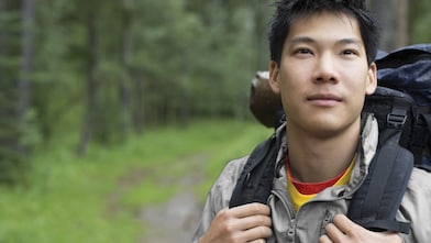 Portrait of Asian male backpacker in the woods