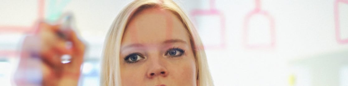 Sweden, Businesswoman writing on glass wall in office