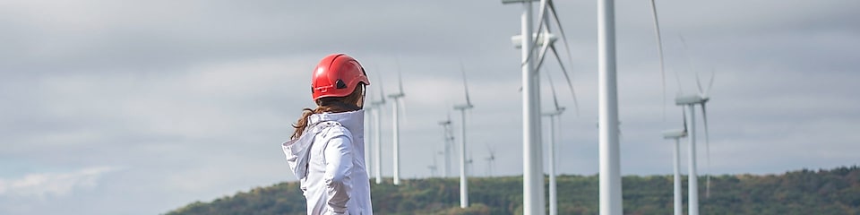 A female Shell employee standing in front of a wind turbine.