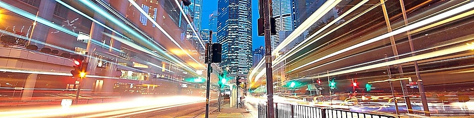 A city scape at night with trailing lights from cars going by.