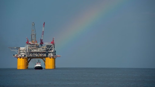 A Shell offshore rig with a rainbow in the background.