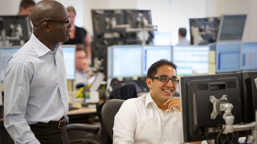 Two traders at Shell working together and smiling.