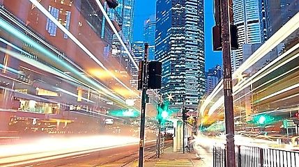A city scape at night with trailing lights from cars going by.
