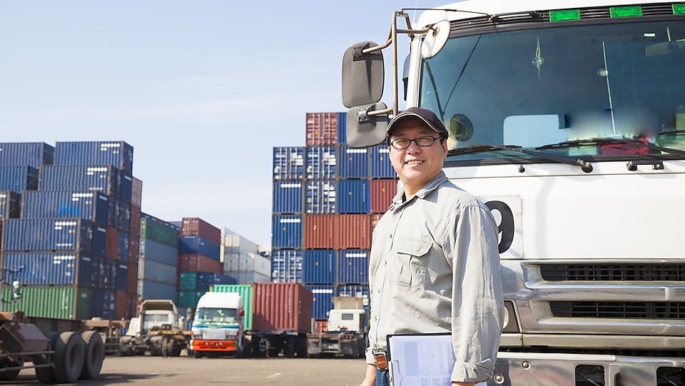 Truck driver with the shipping container and truck in the background