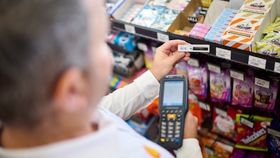 Customers using a mobile phone to make a digital payment at a Shell service station store.