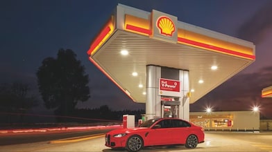Red car refueling at a Shell V-Power station illuminated at night.