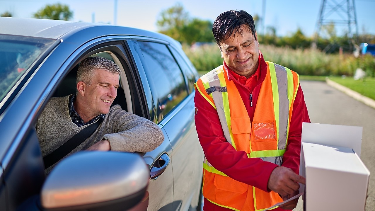 Customer making a QR code payment at a Shell service station while holding a motorcycle helmet.