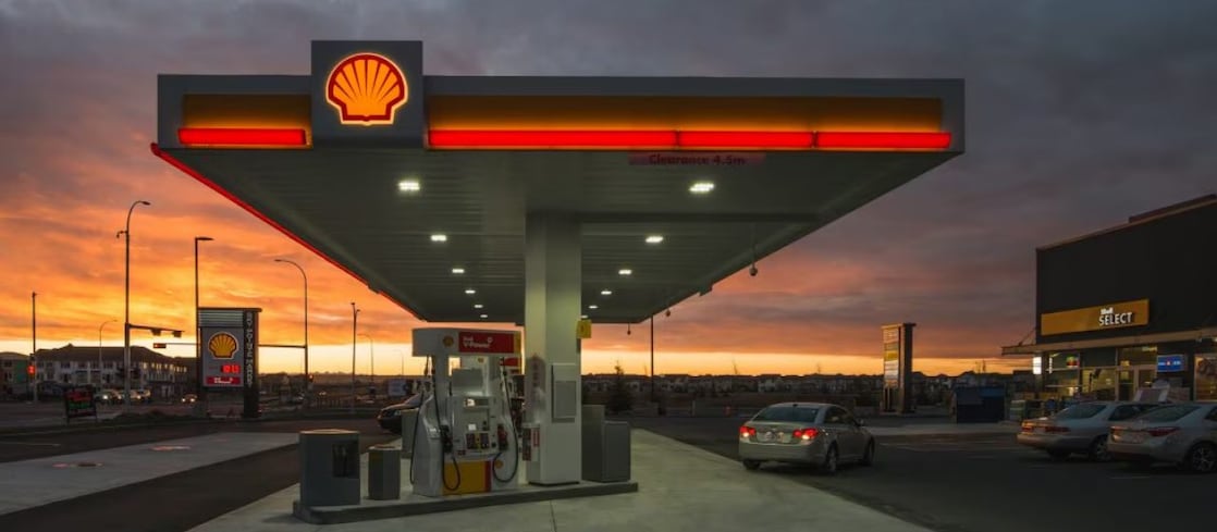 Shell service station at sunset with fuel pumps and Shell Select store in view.