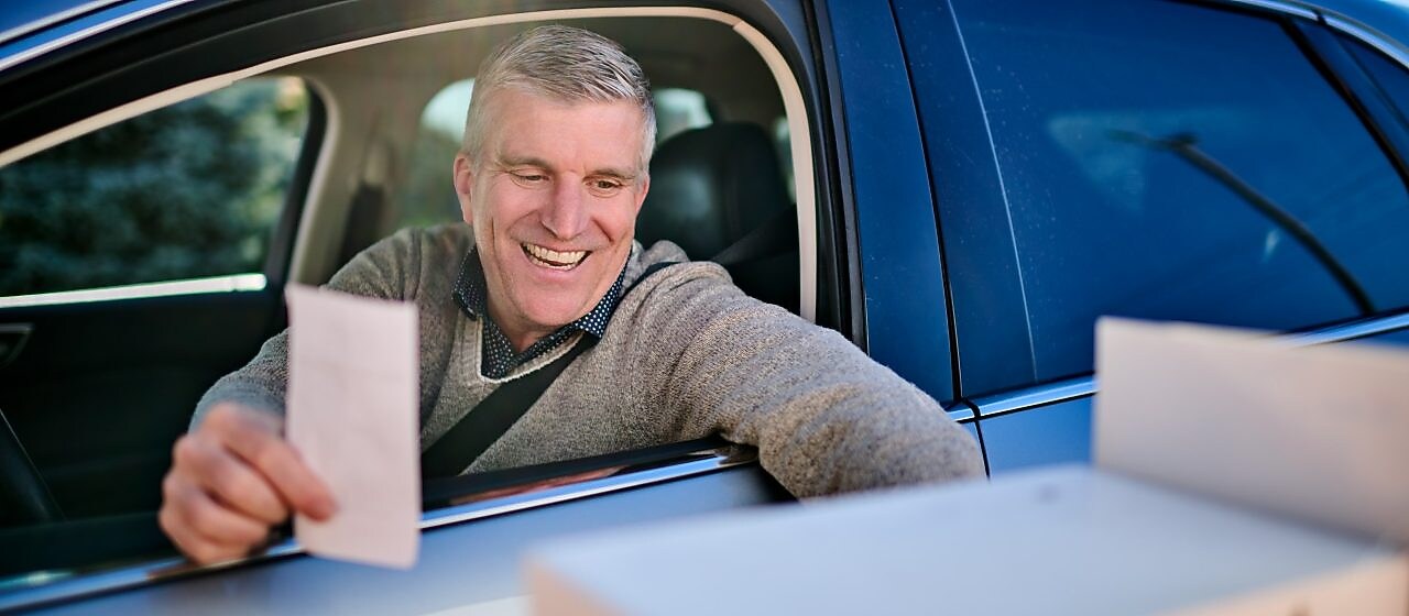 Close-up of the illuminated Shell logo on a fuel station canopy at dusk against a clear evening sky.