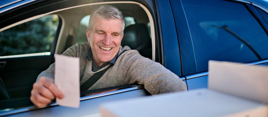 Close-up of the illuminated Shell logo on a fuel station canopy at dusk against a clear evening sky.