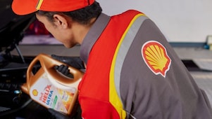Shell service staff member pouring Shell Helix Ultra motor oil into a car engine.