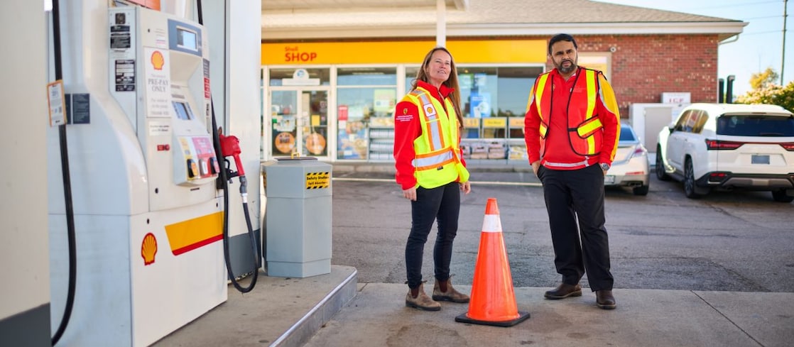 Shell service station canopy with illuminated Shell logo and fuel signs at dusk.