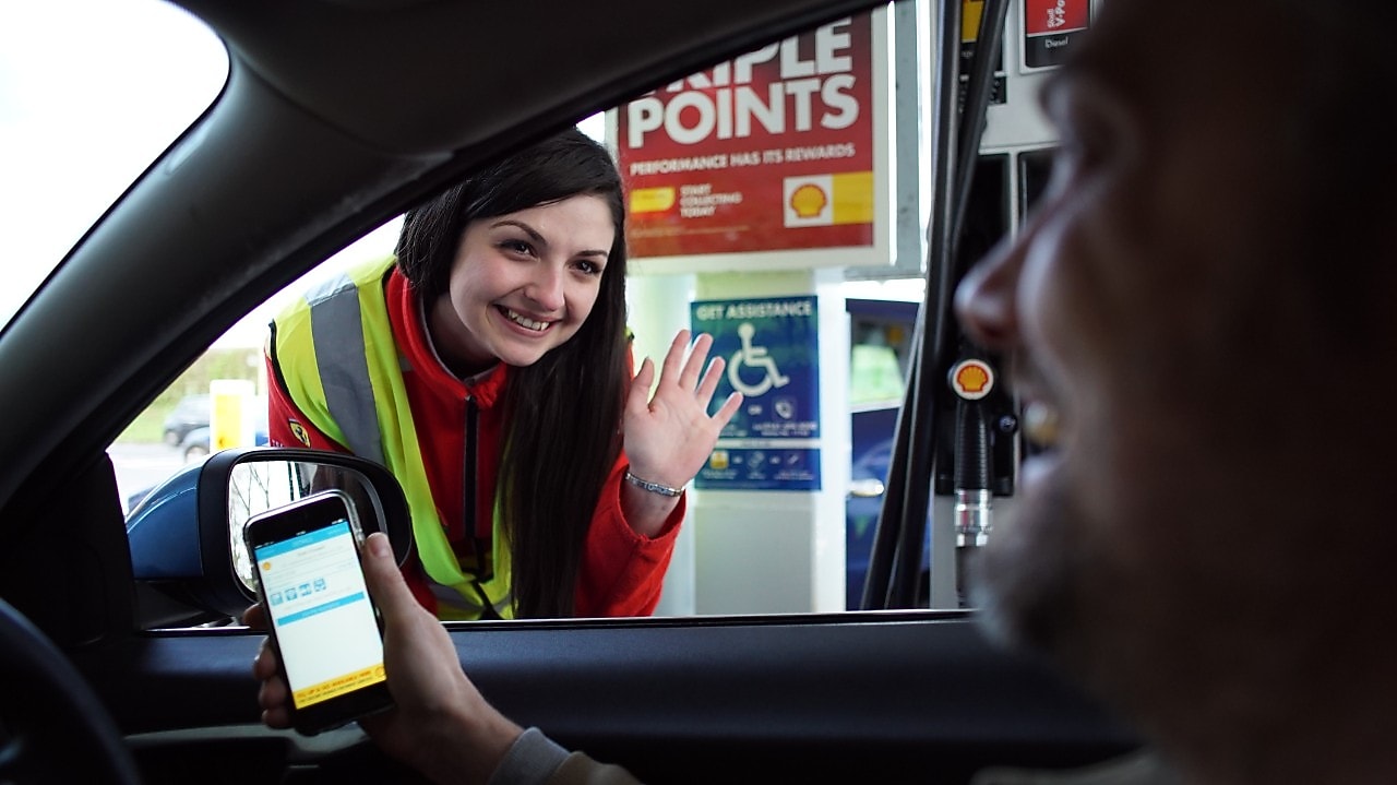 A woman at shell station helps a disabled man to refuel his car