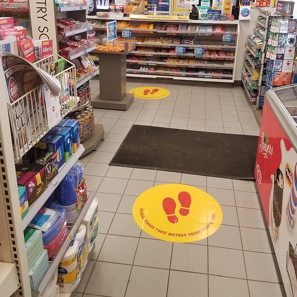 Round yellow floor decals inside a Shell retail store indicate social distancing measures.