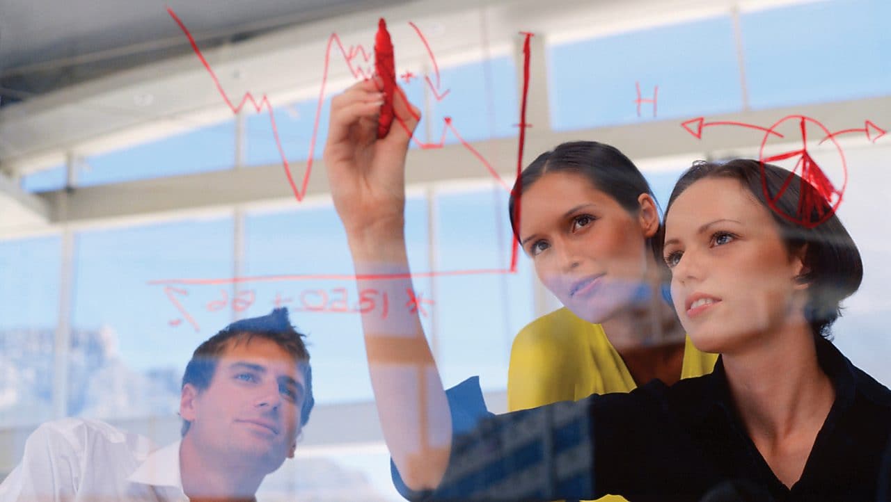 Businesswoman drawing graphs on glass