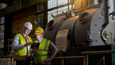 male engineer and worker using digital tablet in dark factory