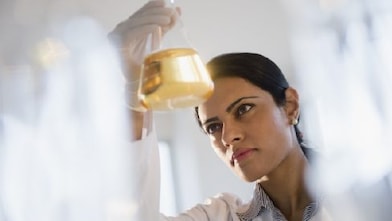 Lab technician looking at a glass vial that holds lubricant