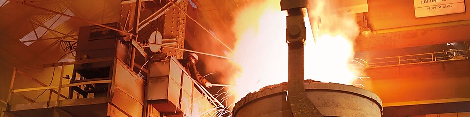 travailleurs observant une lourde machinerie dans une usine de traitement des métaux