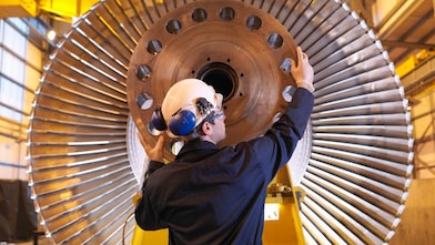 engineer examines turbine parts to help ensure it will deliver