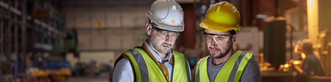 Male engineer and worker using digital tablet in dark factory