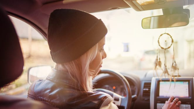Une jeune femme consulte les instructions affichées sur l'écran de navigation intégré de sa voiture