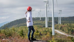 Une employée de Shell devant une éolienne.