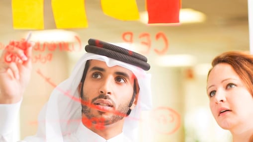 Deux employés de Shell écrivant sur un tableau en verre avec des marqueurs.