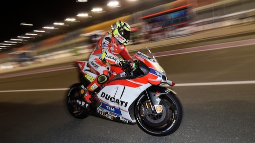 Pilote Ducati roulant vite sur une moto, sur un circuit, de nuit.