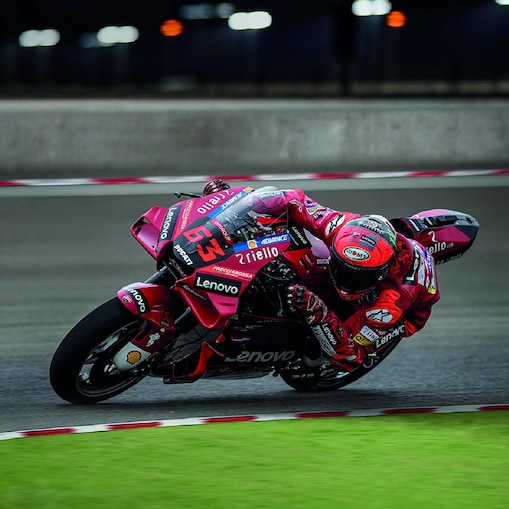 A red Ducati MotoGP bike taking a sharp turn on a race track