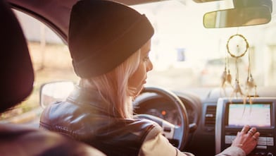 Une jeune femme consulte les instructions affichées sur l'écran de navigation intégré de sa voiture